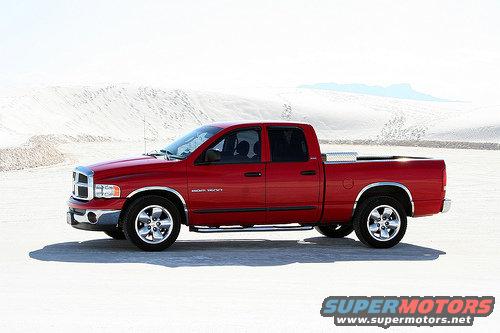 Red Dodge Ram pickup truck, side view, with chrome accents and a toolbox in the bed, parked on a sandy terrain