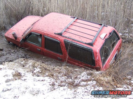 Red SUV stuck in mud and water, with roof rack