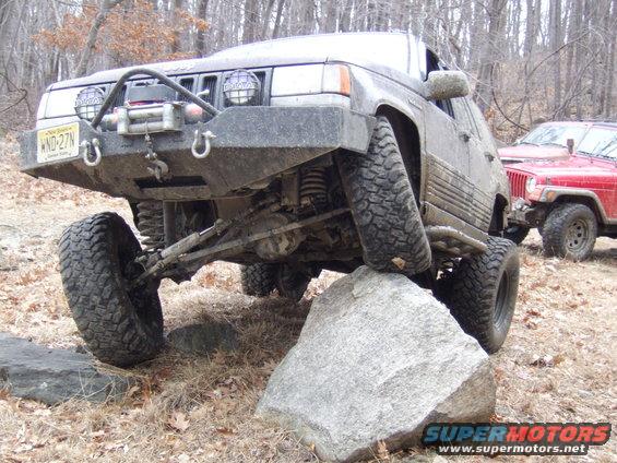 Modified Jeep Grand Cherokee on a rock, another Jeep visible behind it