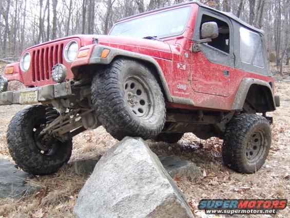 Red Jeep Wrangler climbing over rocks off-road