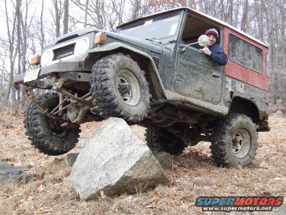 1976 Toyota Land Cruiser 3q-front view, green with red top, off-roading over a rock