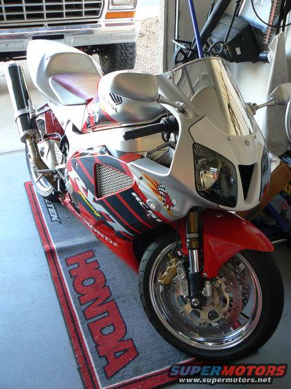 Red and silver Honda sportbike on a Honda mat. Truck in background