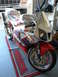1978 Ford Bronco - A red and silver Honda sport motorcycle is parked on a Honda branded mat inside a garage.