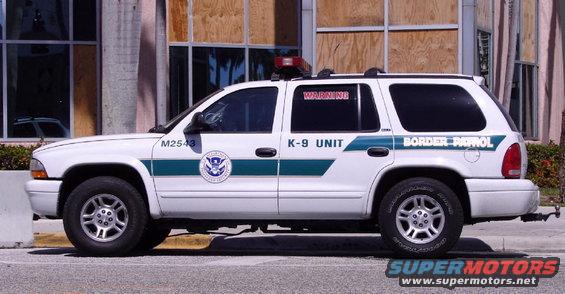 White SUV with green stripe, "Border Patrol" and "K-9 UNIT" text, and a light bar