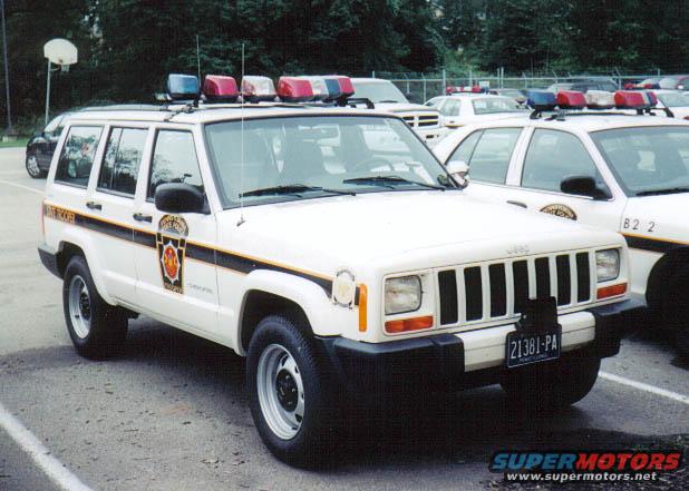 White Jeep Cherokee police SUV with light bar, side stripe, and Pennsylvania license plate 21381-PA
