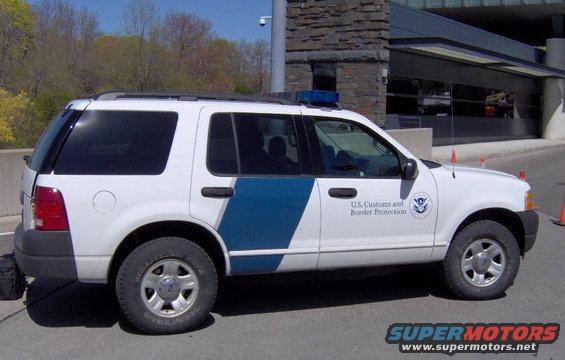 White Ford SUV with U.S. Customs and Border Protection markings and a blue light bar on the roof