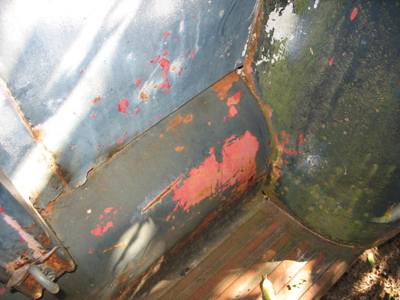 Rusty interior of a truck bed with peeling paint and visible floor ribs