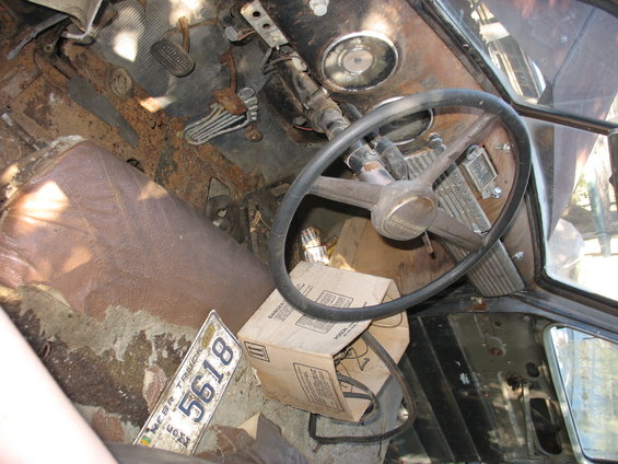 Rusty truck interior with cracked dashboard, worn seat, and a license plate reading 5618