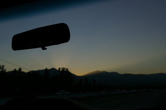 view from inside car looking at rearview mirror, sunset behind mountains