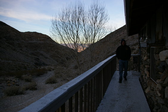 Person walks on walkway by stone building in desert at dusk