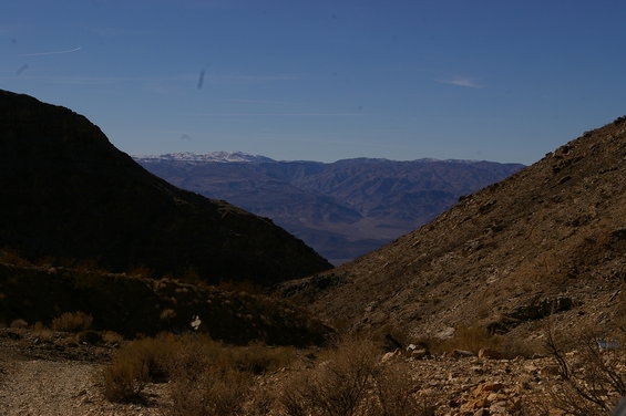 Mountain landscape with snow-capped peaks in the distance, viewed through a rocky canyon