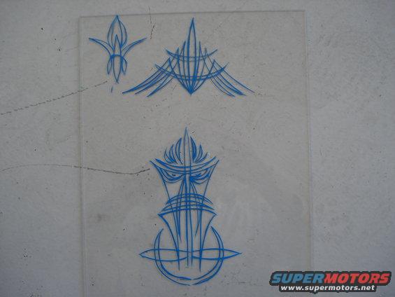 Blue pinstripe art on clear plastic sheet, showing three designs including a flame-like shape and a stylized face
