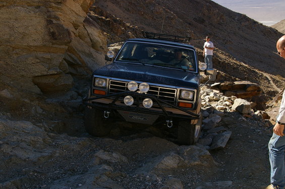 Dark blue 1986 Ford Bronco on rocky trail with aftermarket bumper and lights
