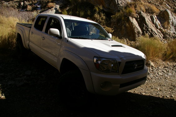 White Toyota Tacoma pickup truck on a rocky, off-road path