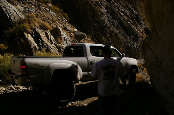 White Toyota Tacoma TRD Sport pickup truck on a narrow, rocky mountain road