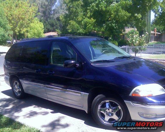 Blue 2000 Ford Windstar minivan with chrome wheels and silver lower body trim, parked on a driveway