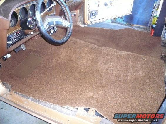 1975 Ford Ranchero interior showing new brown carpet laid out, dashboard and steering wheel visible