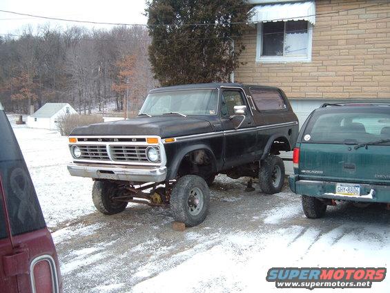 Black Ford Bronco with lifted suspension, front 3/4 view, parked on gravel with snow