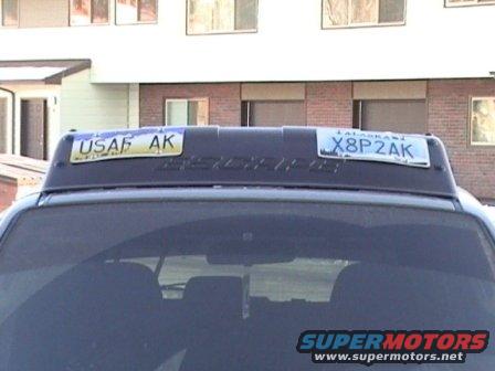 Dark SUV rear view with roof rack holding two license plates, one reads USAF AK, the other X8P2AK