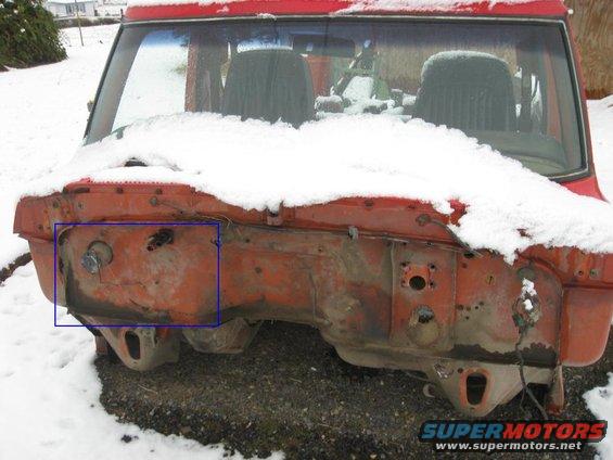Red vehicle firewall covered in snow, showing exposed metal and mounting points