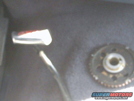 Close-up of a metal gear with teeth and a central hole, next to a shiny metal object with red markings