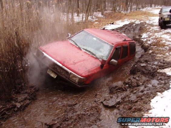 Red SUV stuck in mud, another vehicle visible in background