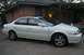 2003 Acura TL - A white sedan is parked in front of a brick house with a covered porch.