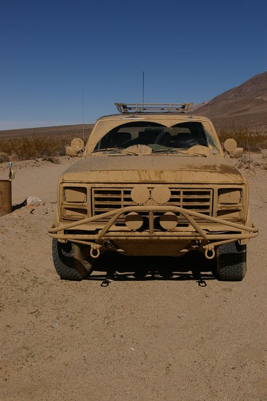 Tan pickup truck with off-road bumper and roof rack parked in desert