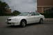 2003 Acura TL - A white 2003 Acura TL is parked in a lot with buildings and trees in the background.