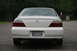 2003 Acura TL - The rear of a white sedan is shown, its taillights and dual exhaust pipes.