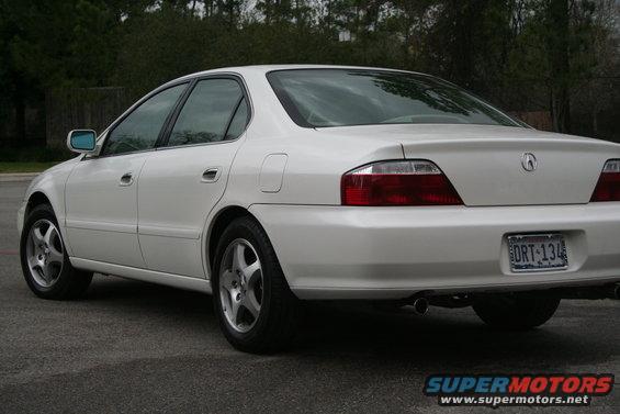 White 2003 Acura TL sedan, rear 3/4 view, showing taillights, license plate, and dual exhaust