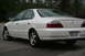 2003 Acura TL - A white 2003 Acura TL sedan is viewed from the rear 3/4 angle, displaying its distinctive taillights and license plate.