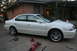 2003 Acura TL - A white 2003 Acura TL is shown with its front passenger side wheel removed and the vehicle supported by jack stands and a floor jack.