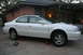 2003 Acura TL - A white 2003 Acura TL is parked on jack stands, with a jack and lug wrench nearby.