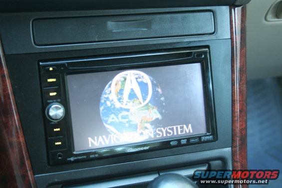 Car dashboard showing an Acura navigation system screen with the Acura logo and a globe
