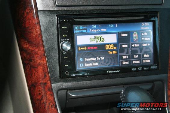 Close-up of car dashboard showing Pioneer stereo display with XM radio info and wood trim