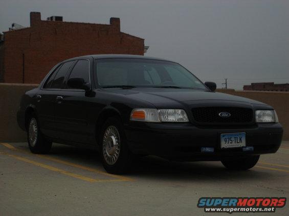 Black Ford Crown Victoria parked in a lot. License plate reads 975-TLK