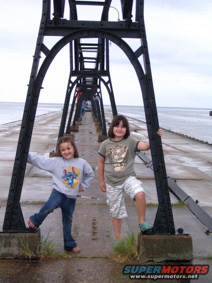 Two girls on a pier with a metal structure overhead