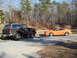 1995 Ford Mustang - An orange 1995 Ford Mustang coupe is parked next to a lifted black SUV.