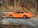 1995 Ford Mustang - Side view of an orange 1995 Ford Mustang coupe parked outdoors.