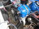 1985 Ford Crown Victoria LTD - Close-up view of a blue aftermarket alternator mounted on an engine, with belts and pulleys visible.