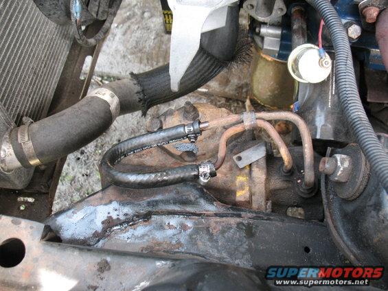 engine bay with hoses, lines, and some rusty metal parts
