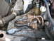 1985 Ford Crown Victoria LTD - Close-up view of engine components, including hoses and metal tubing, with visible rust on the frame.
