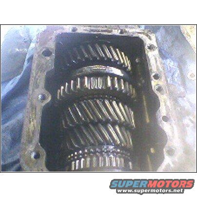 Transmission gears inside a metal casing, covered in dark grease