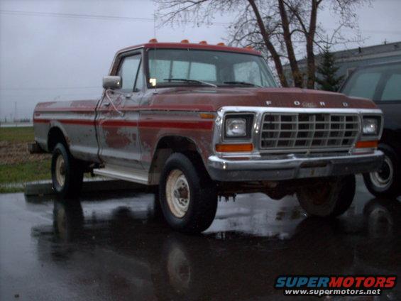 Red and silver Ford F-250 pickup truck from 1979, parked outside on a wet day