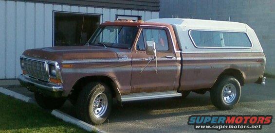 Brown Ford pickup truck with a white camper shell, parked outside a building