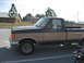 1981 Ford Bronco - This Ford F-150 pickup truck is parked outside a building with trees and a fence in the background.
