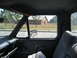 1981 Ford Bronco - View from inside a truck cab, looking out at a brick building and trees.