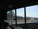 1981 Ford Bronco - View from the interior of a vehicle, looking out the rear window at a fence and trees under a clear sky.