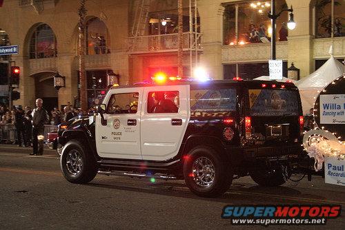 Black and white Hummer H2 police SUV with flashing lights, side view